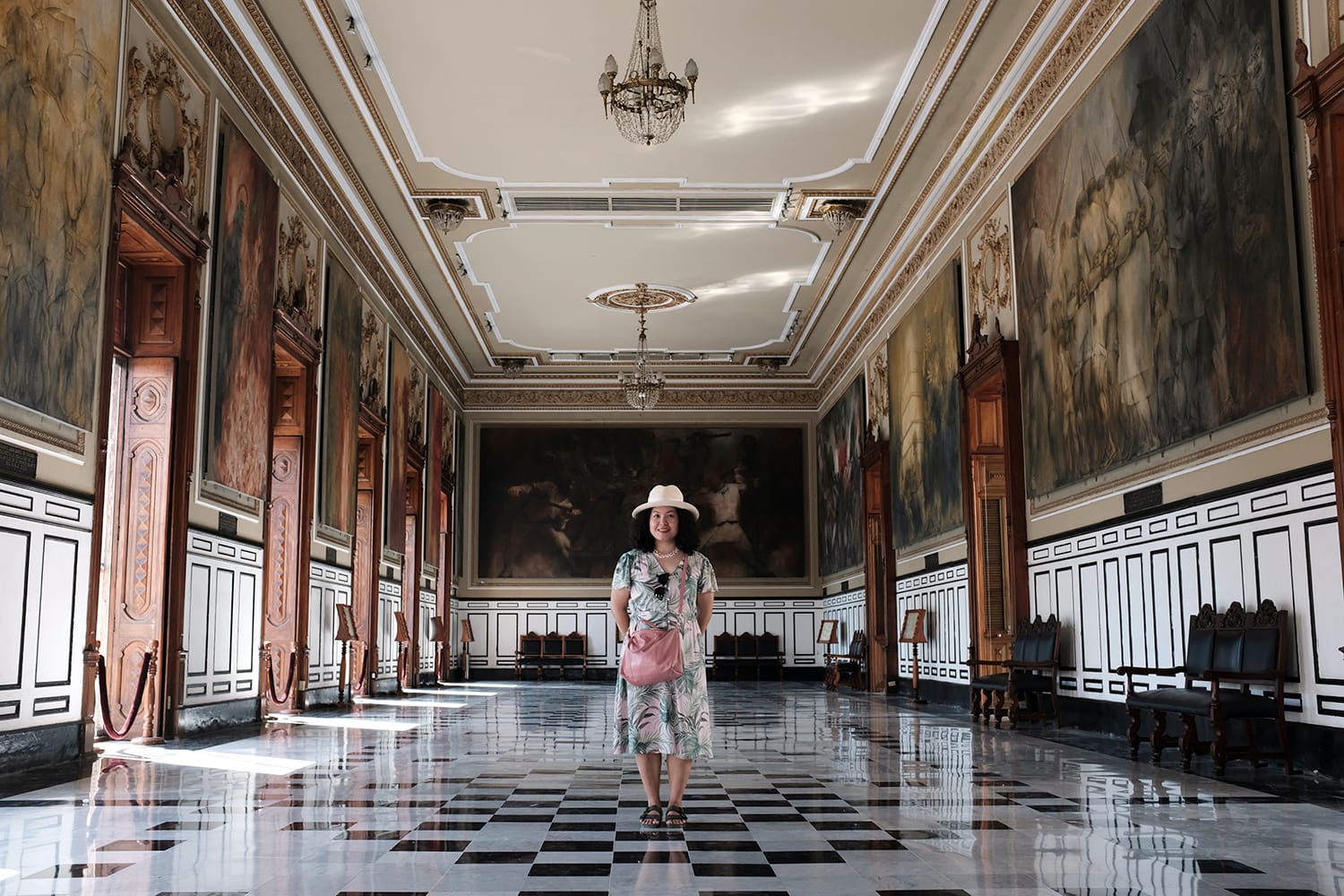 An Asian female tourist is posing for a picture inside the main hall of Government Palace - Palacio del Gobierno in Main Square, Merida, Yucatan, Mexico.