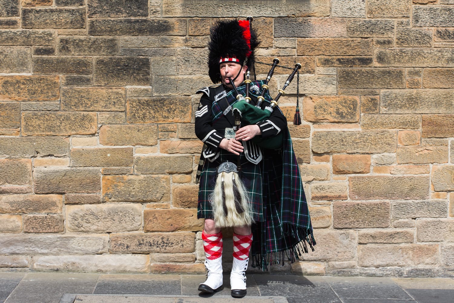 A bagpiper, a street musician wearing kilt and traditional scottish costume