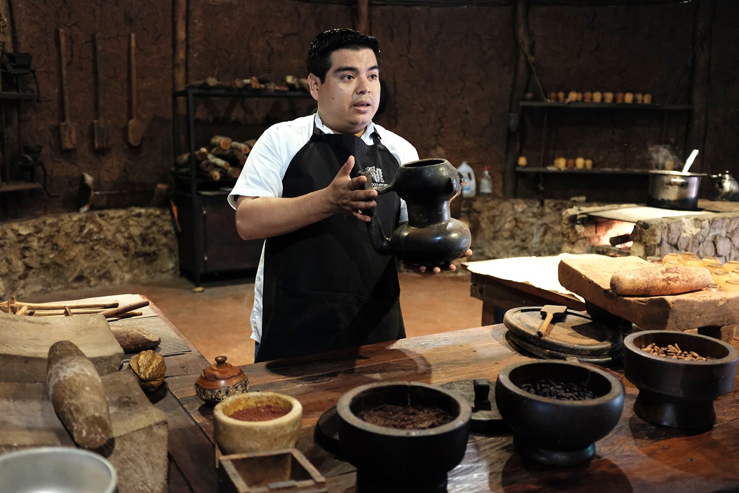 Ένα τοπικό μεξικανό προσωπικό στο μουσείο σοκολάτας εξηγεί τη διαδικασία του πώς να φτιάξετε ένα ρόφημα σοκολάτας των Μάγια από κόκκους κακάο.