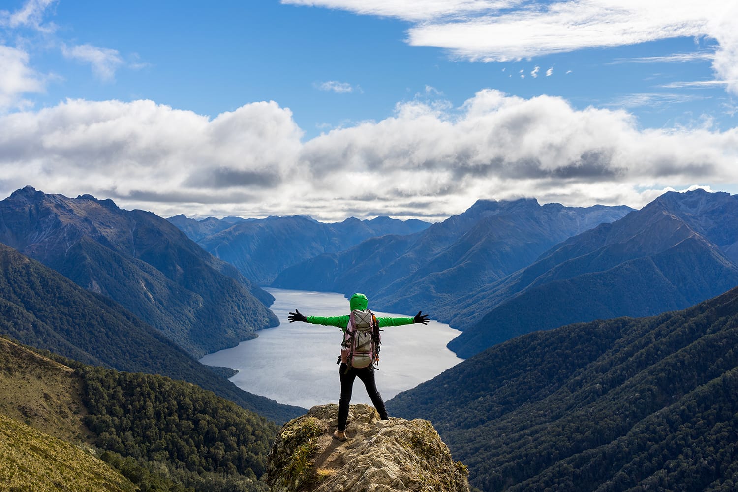 Woman hiker on mountain cliff. Kepler Track, New Zealand