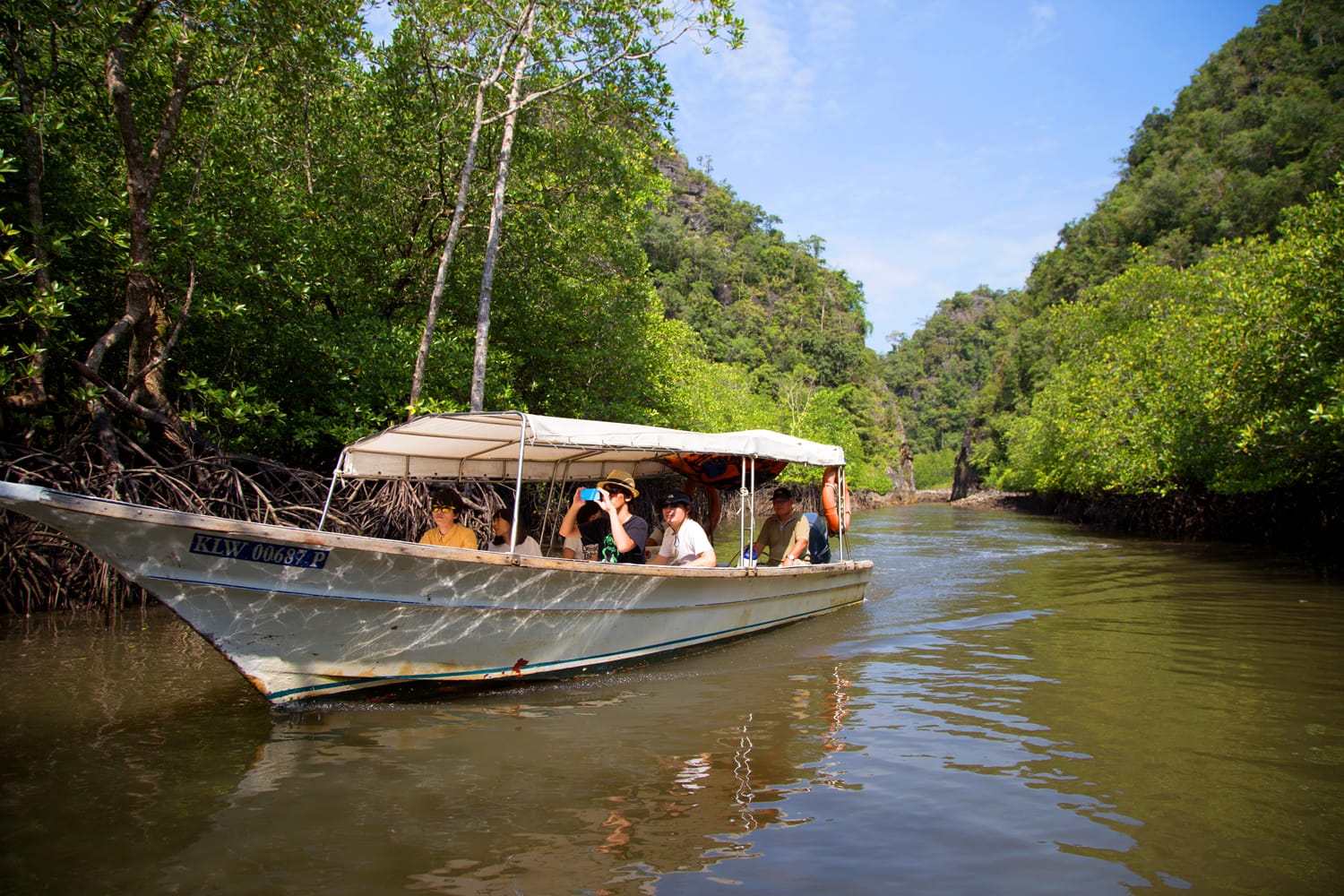 Tourists travel by boat at Kilim Karst Geoforest park in Langkawi, Malaysia