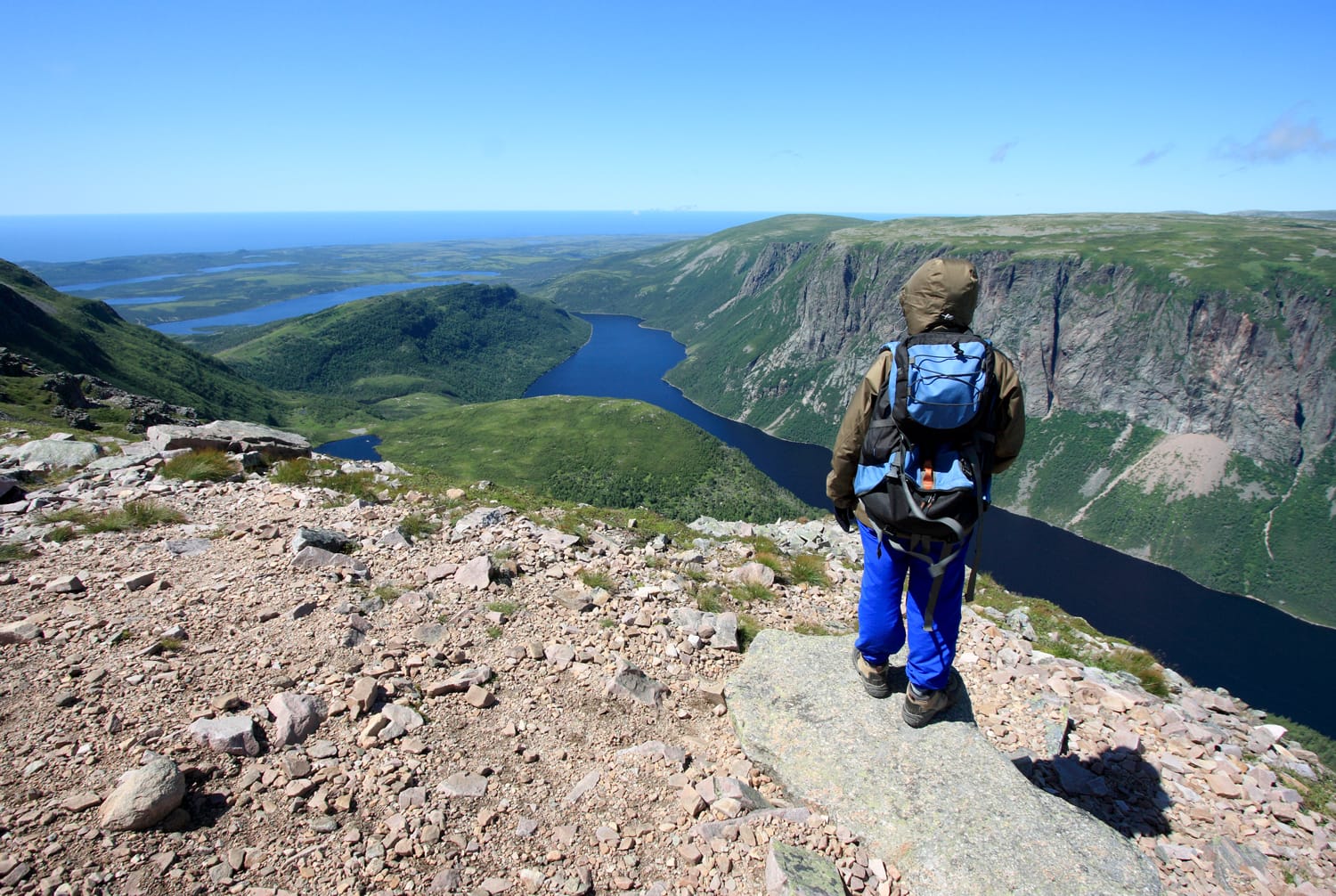 A female hiker standing on Gros Morne Mountain above Ten Mile Pond in Gros Morne National Park, Newfoundland, Canada.