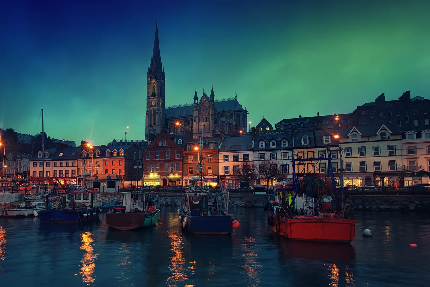 Port, houses, restaurants, shops, bars, pubs and Cathedral at night in Cobh, Ireland