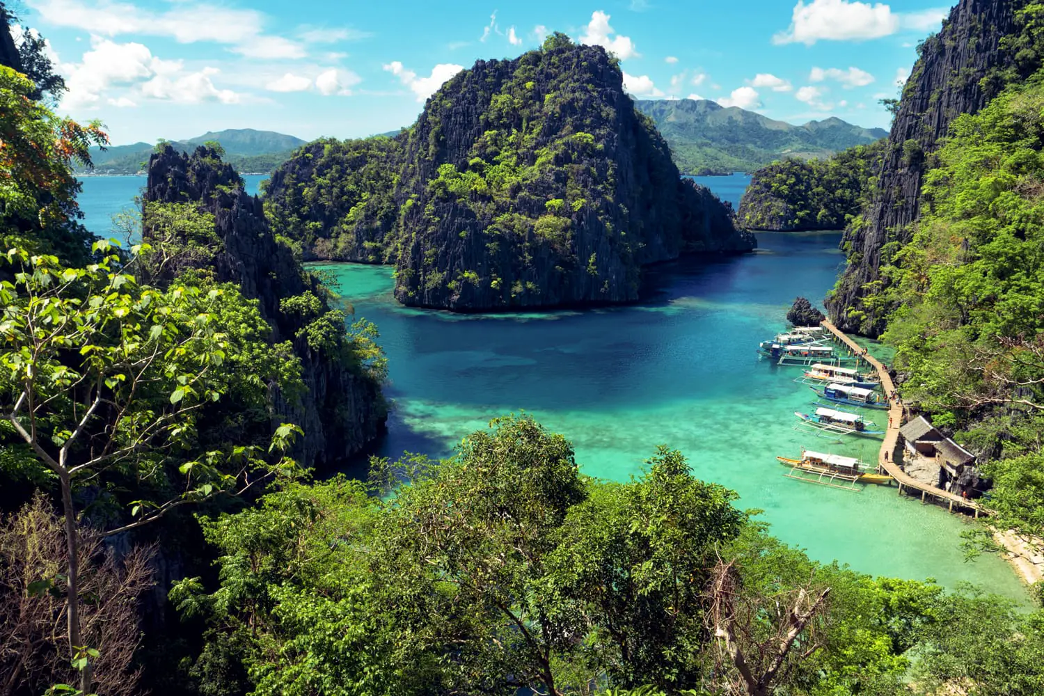 Elevated view of lagoon with boats surrounded by rocks and turquoise sea. Coron. Palawan, Philippines