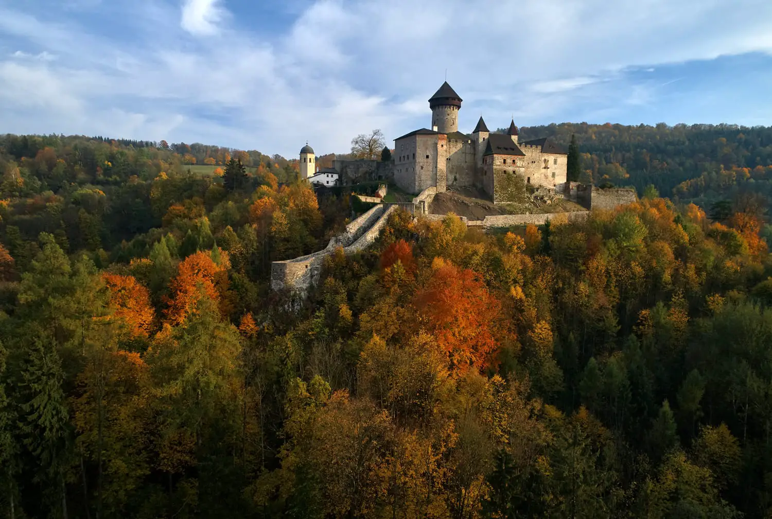 Aerial view on Castle Sovinec, Eulenburg, robust medieval fortress, one of the largest in Moravia, Czech republic. Czech landscape with medieval castle on a rocky hill above a forest valley, autumn.