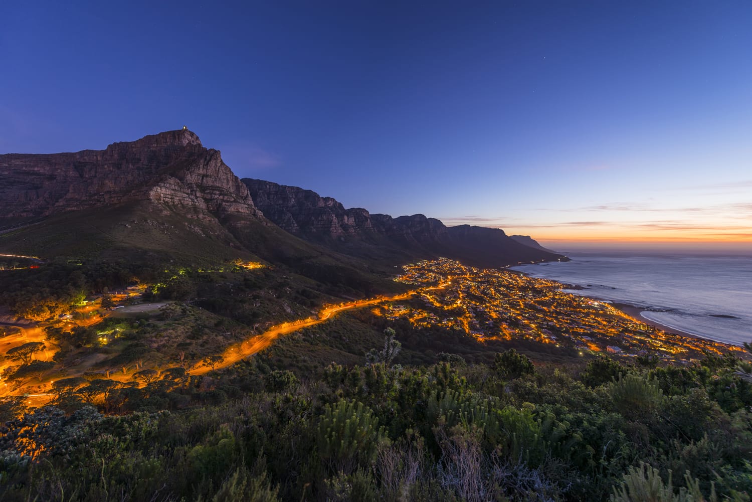 Το Cape Town's Table Mountain & Twelve Apostles φαίνεται από την κορυφή Lions Head πεζοπορίας και το Twelve Apostles με το προάστιο του κόλπου κατασκηνώσεων και τον ωκεανό κάτω