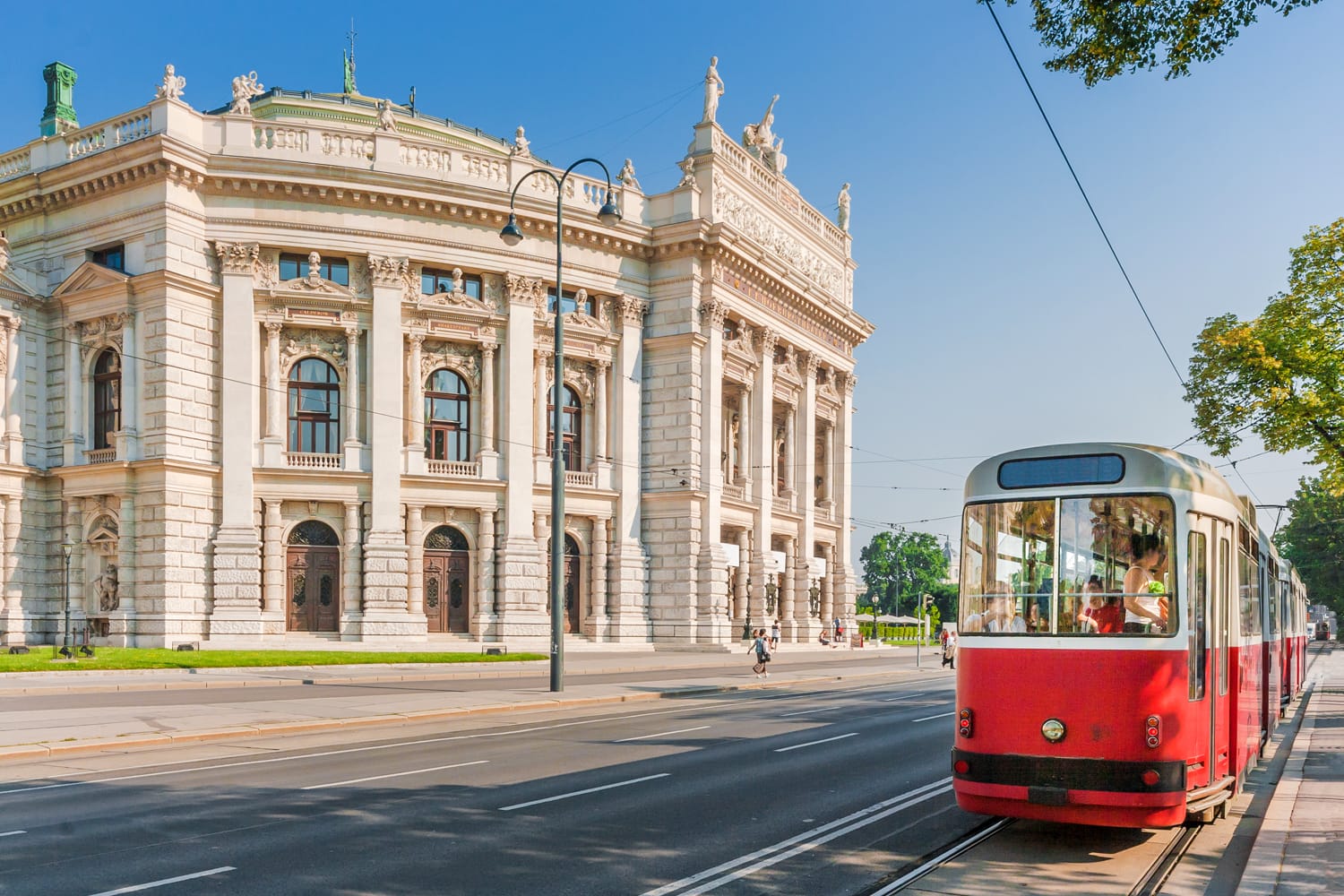 Famous Wiener Ringstrasse with historic Burgtheater (Imperial Court Theatre) and traditional red electric tram at sunset in Vienna, Austria