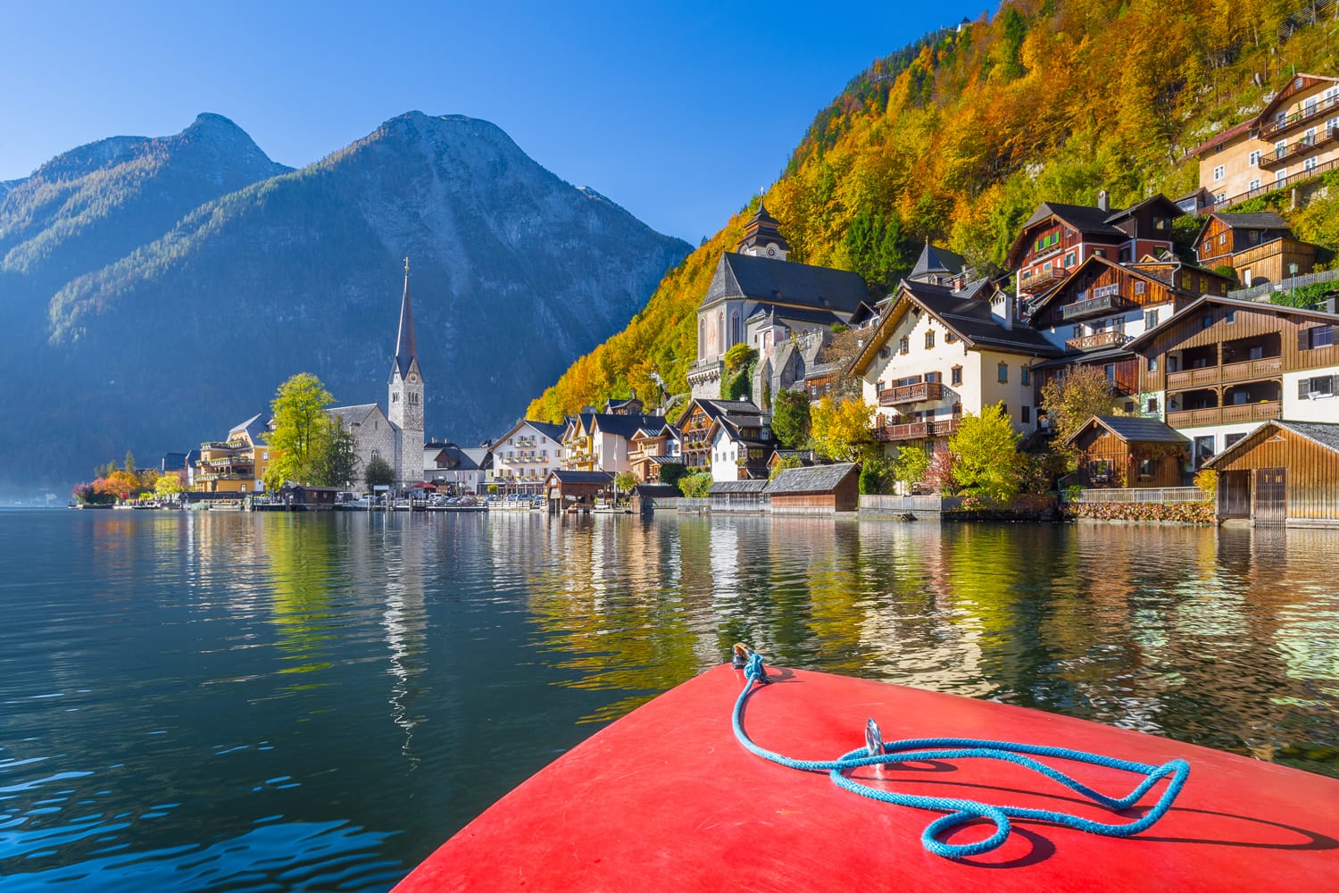 Scenic picture-postcard view of famous Hallstatt mountain village during a boat tour on Hallstatter See in the Austrian Alps in beautiful golden morning light in fall, region of Salzkammergut, Austria