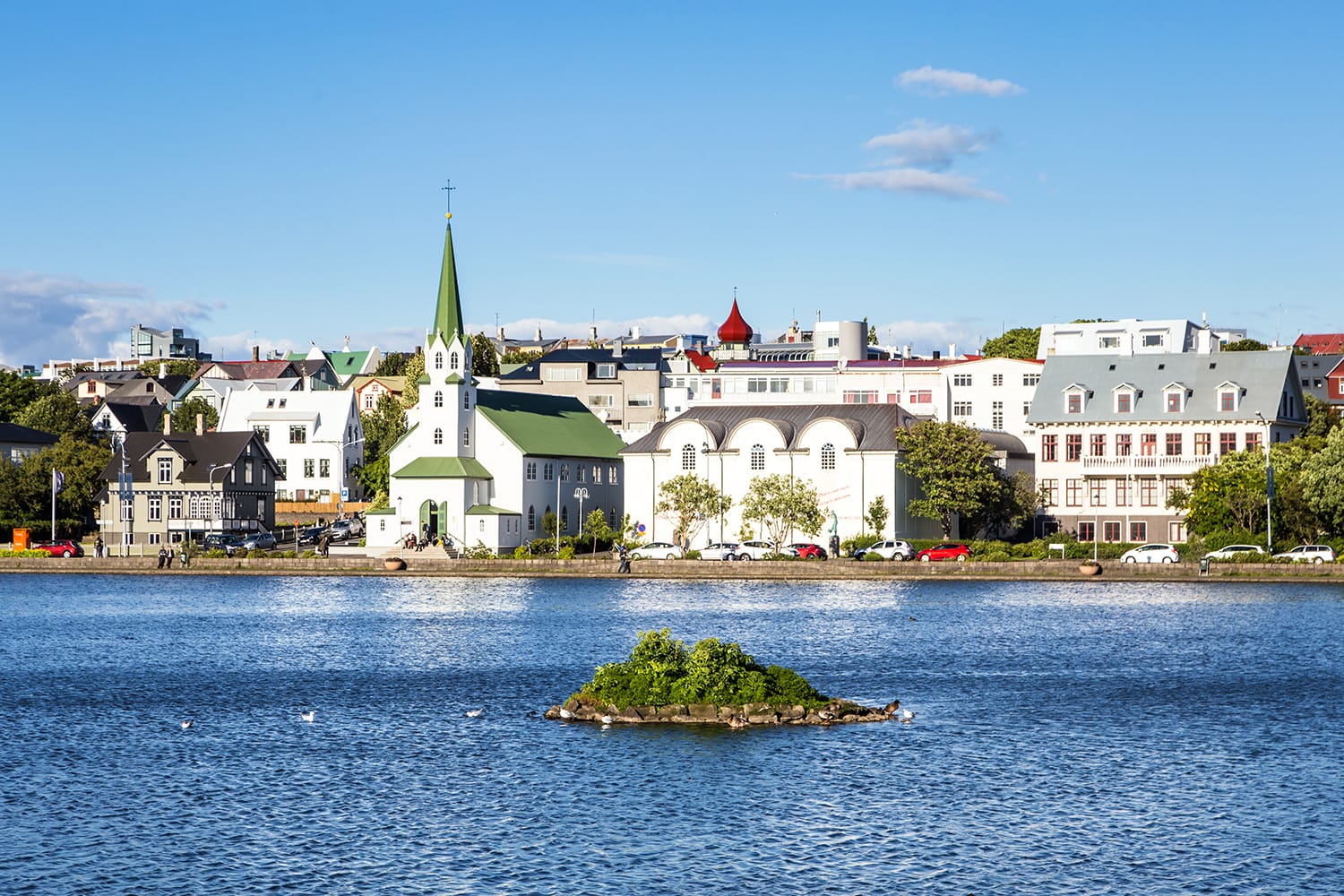 Reykjavik cityscape viewed from across the Tjornin lake in the heart of Iceland capital city on a sunny summer day.
