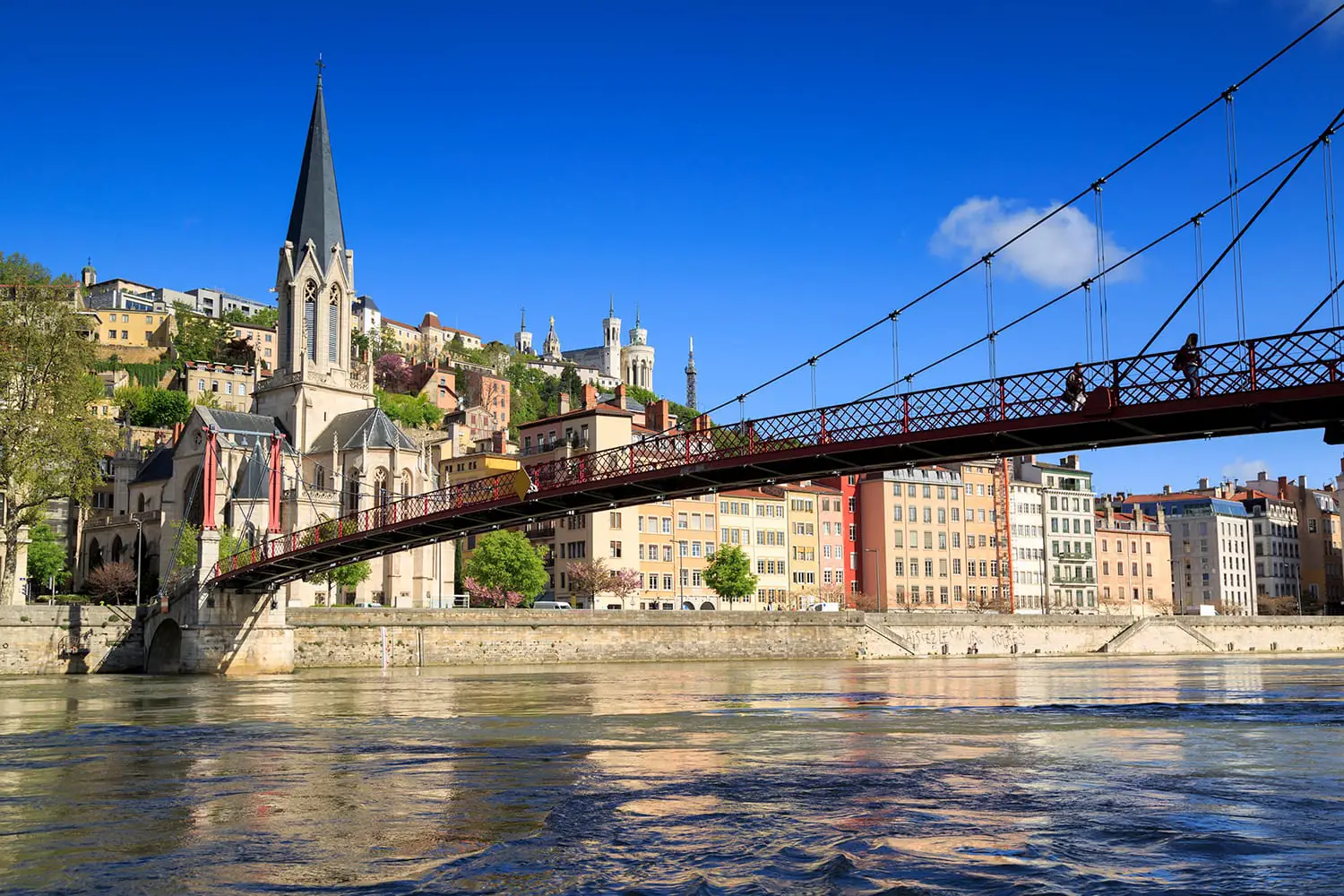 Pedestrians on the Saint Georges footbridge and the Saint Georges church in Lyon, France