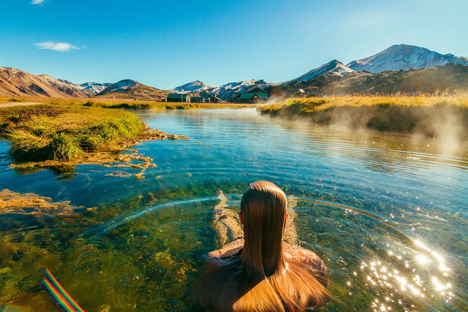 Beautiful female back packer traveler relaxing in the natural hot springs of Landmannalaugar, Iceland