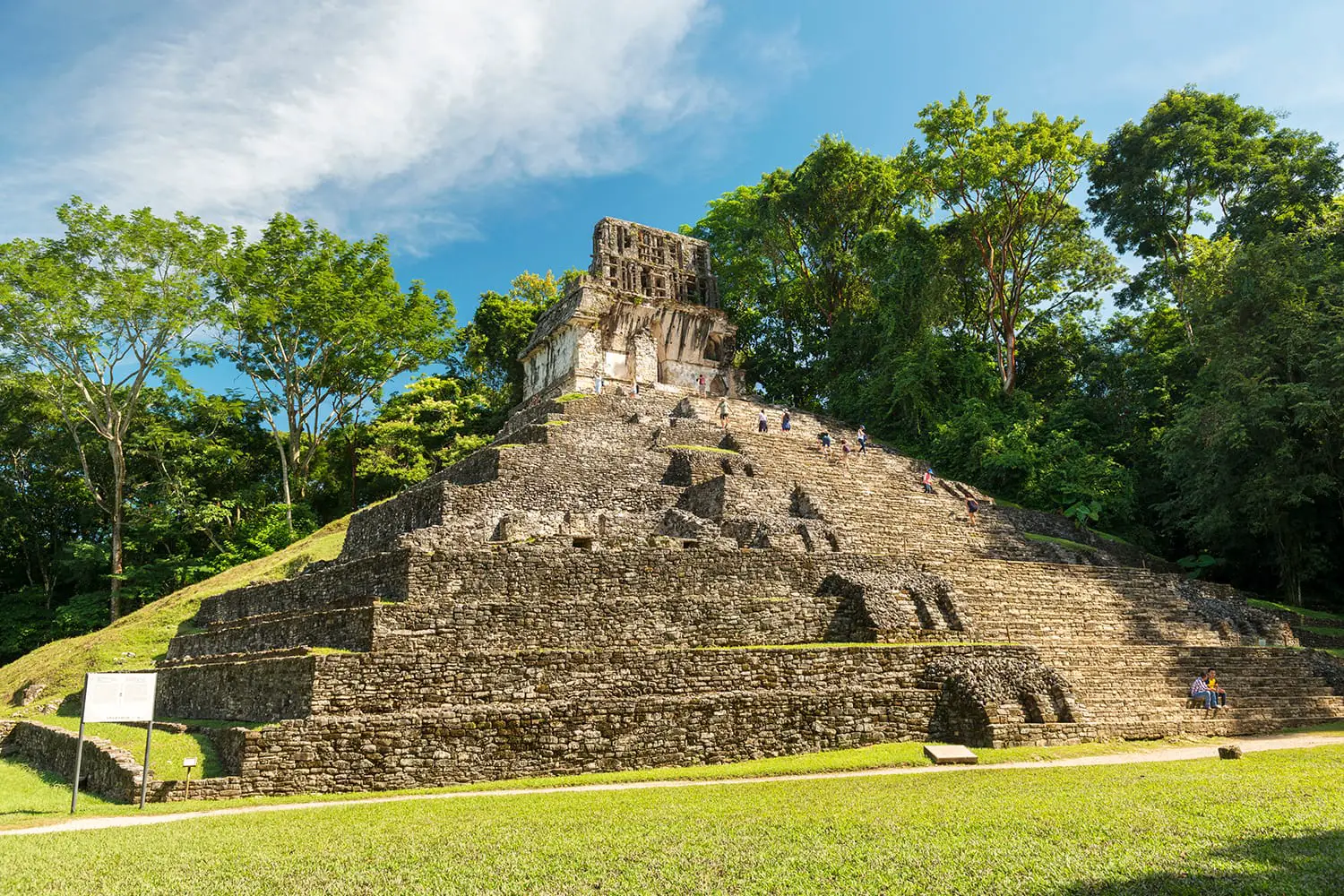 Unknown people explore the mayan temple ruins surrounded by dense jungle in Palenque Mexico