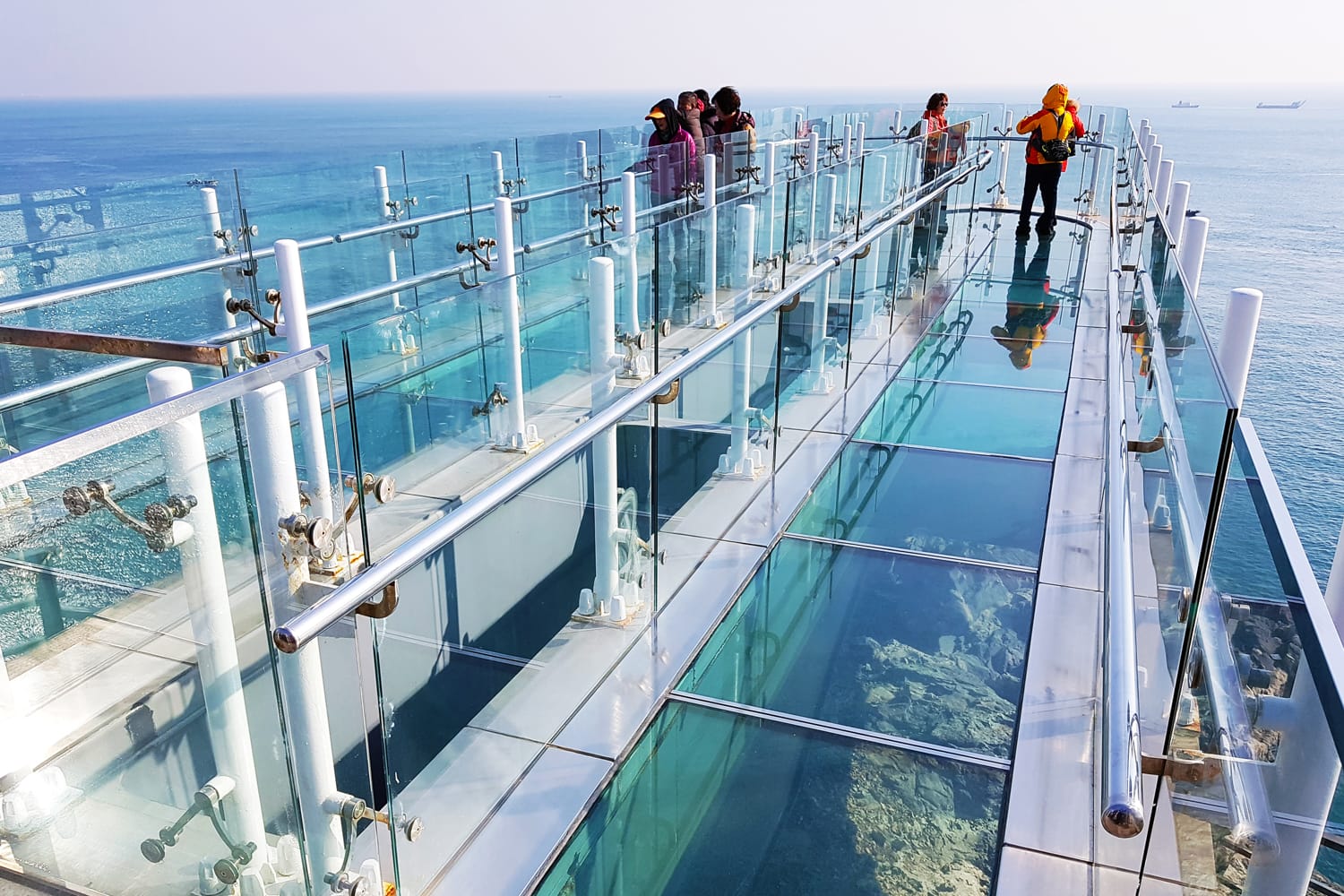 Many tourists standing at Oryukdo Skywalk, the glass bridge seascape viewer, one of famous landmark on the peak of rock mountain in Oryukdo City, South Korea