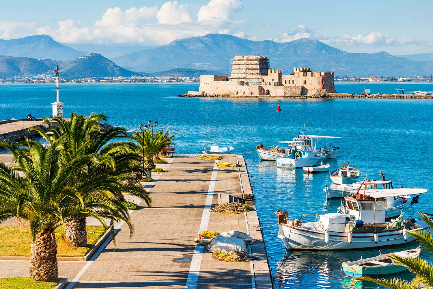 Όμορφο λιμάνι της πόλης του Ναυπλίου στην Ελλάδα με τις μικρές βάρκες, τους φοίνικες και το κάστρο Μπούρτζι στο νερό