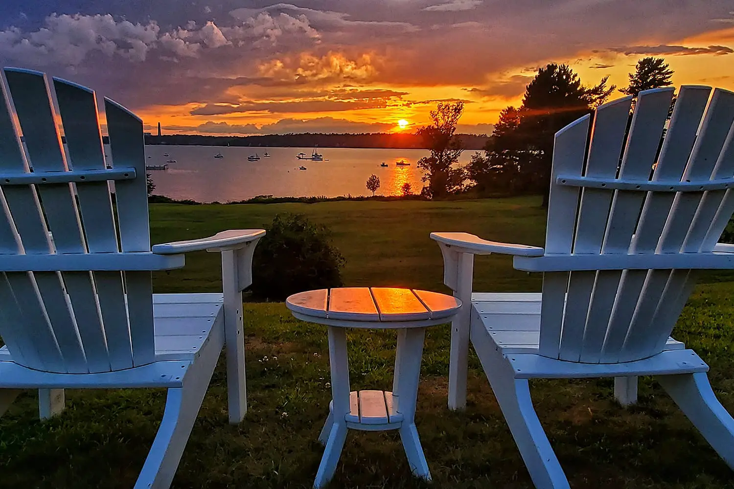 Two empty chairs overlooking a sunset on Chebeague Island, Maine, USA