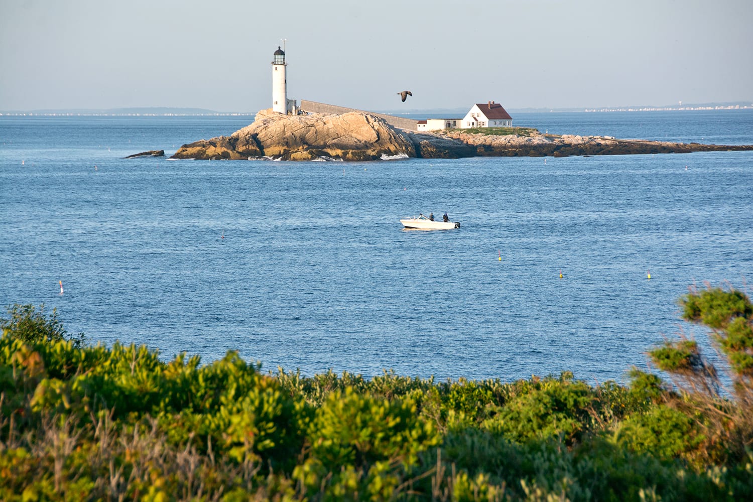 Early morning fishermen try their luck in the strait between Star Island and White Island on a clear summer day. Rye, NH, USA