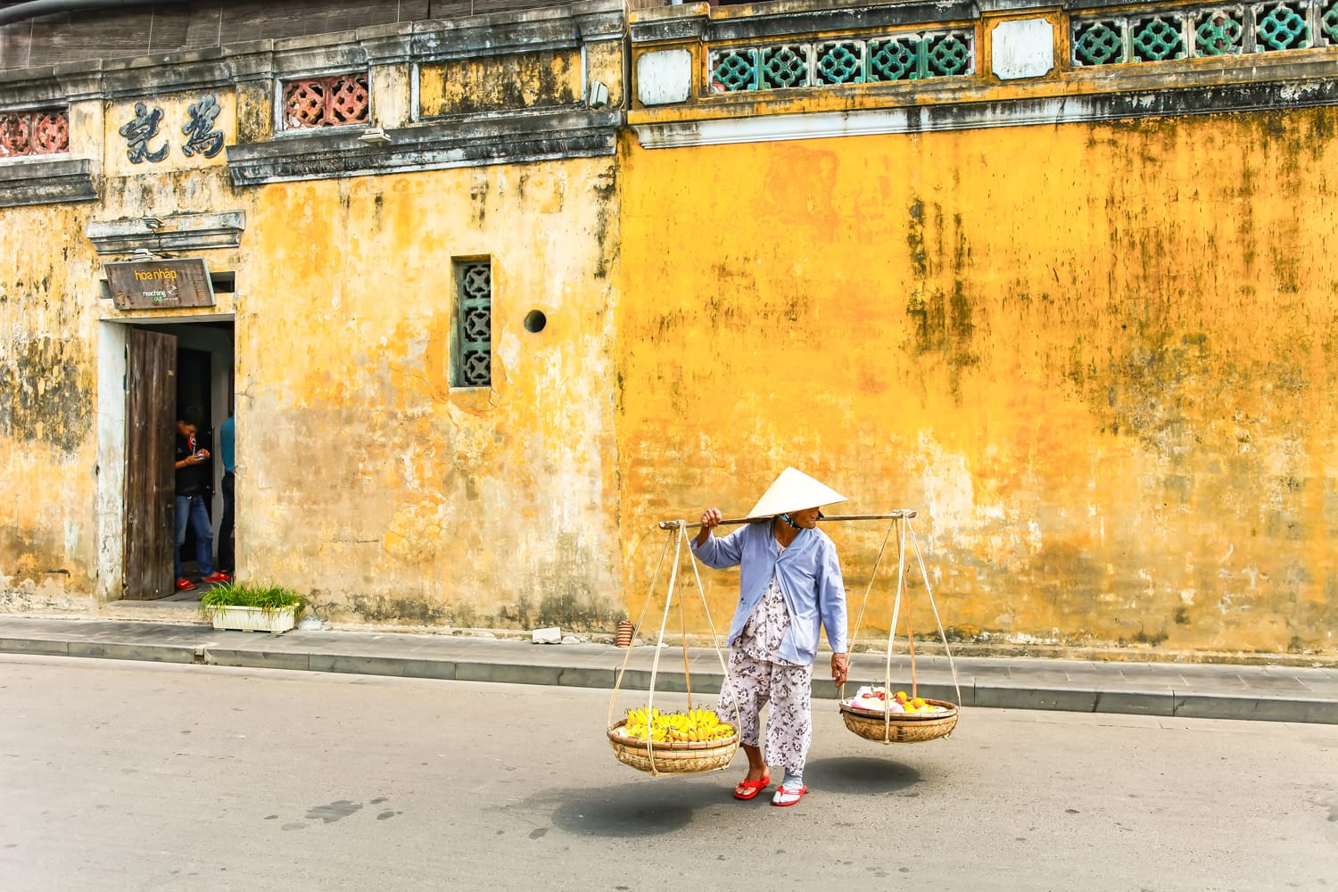 Βιετναμέζα πλανόδιος πωλητής στο Χόι του Βιετνάμ στην αρχαία πόλη Χόι Αν με θέα στα τυπικά κίτρινα σπίτια