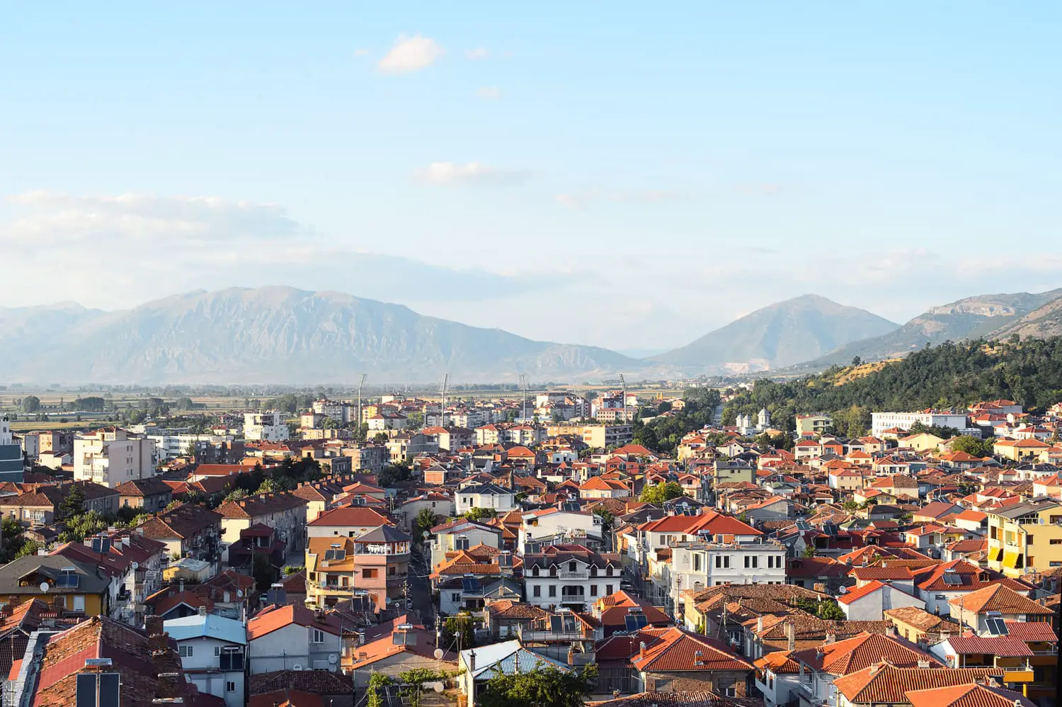 Panoramic aerial view to Korca, the town in southwest of Albania, the mountains and the red tile roofs of its buildings.