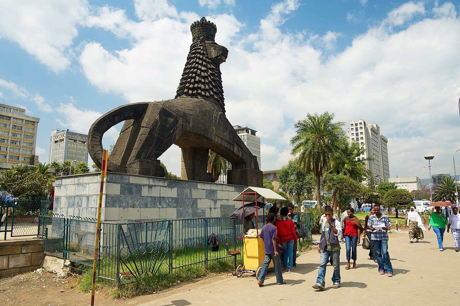 Άγνωστοι περπατούν στον δρόμο δίπλα στο εμβληματικό άγαλμα του λιονταριού του Ιούδα στην Αντίς Αμπέμπα της Αιθιοπίας.