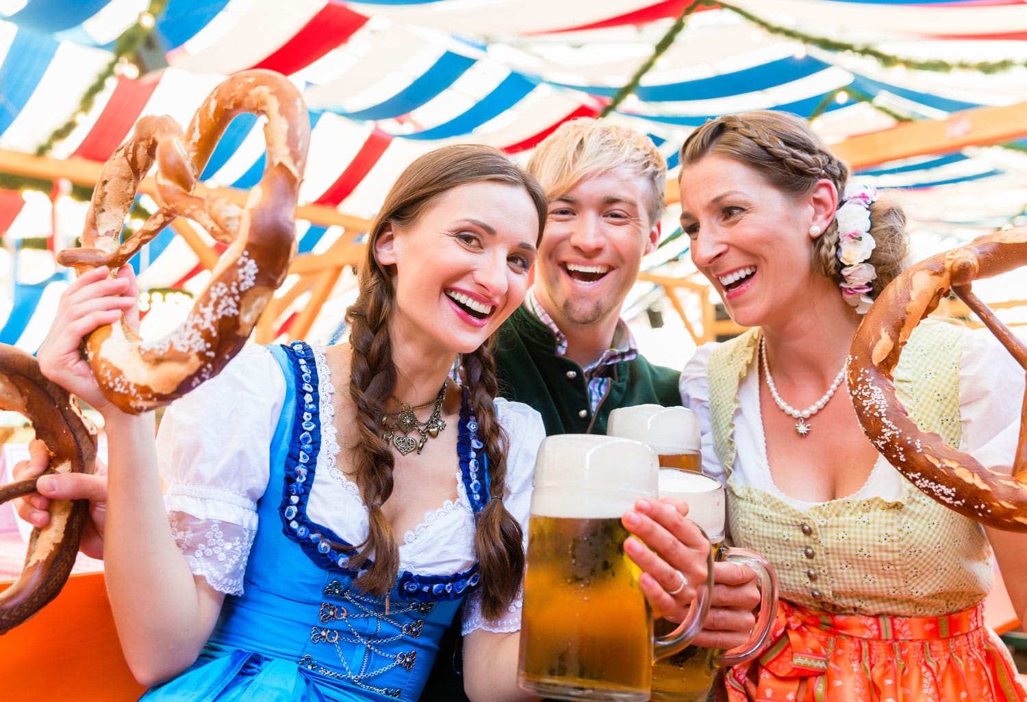 Τρεις φίλοι σε σκηνή μπύρας στο Dult ή στο Oktoberfest κρατώντας γιγάντια κουλούρια στον αέρα