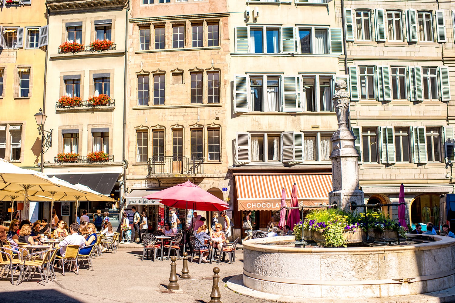 Η πλατεία Bourg-de-four με κόσμο που κάθεται σε καφέ και εστιατόρια.  Είναι η παλαιότερη πλατεία και το πιο δημοφιλές σημείο συνάντησης στη Γενεύη της Ελβετίας