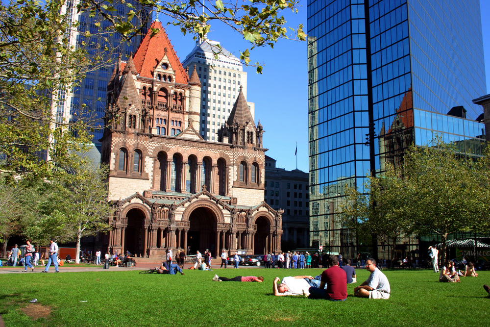 Άνθρωποι που απολαμβάνουν το ανοιχτό καταπράσινο πεδίο μπροστά από μια παλιά κατασκευή που περιβάλλεται από μοντέρνα κτίρια την καλύτερη στιγμή για να επισκεφθείτε τη Βοστώνη.